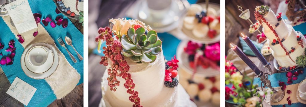 Gedeck udn Hochzeitstorte mit Blumen und Beeren auf einem alten vintage Holz-Esstisch fuer eine Hochzeit in einer Scheune