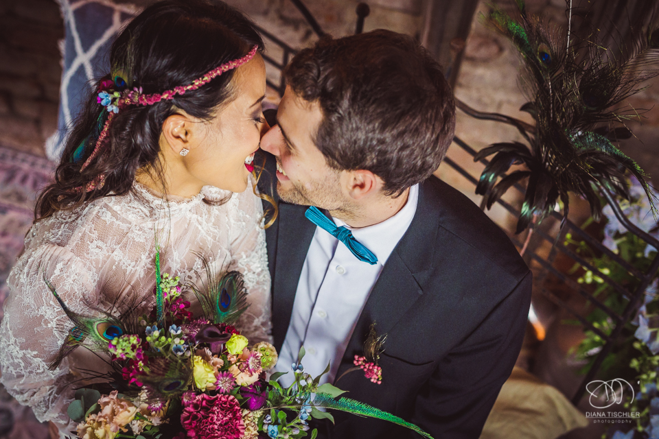 Braeutigam und Braut mit tollem buntem Brautstrauss kuessen sich bei einer Hochzeit in einer Scheune