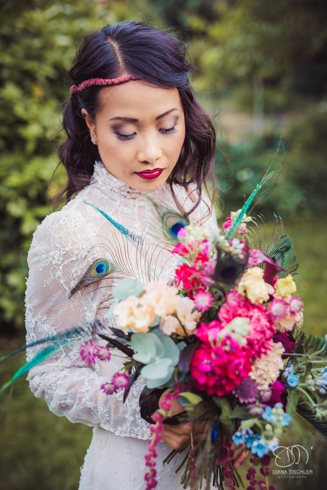 Braut mit tollem buntem Brautstrauss und mit romantischem vintage Boho Kleid bei einer Hochzeit in einer Scheune