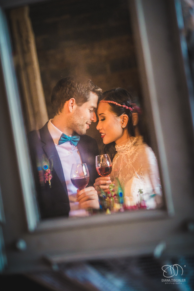 Brautpaar im Spiegel stoesst mit Wein an bei einer Hochzeit in einer Scheune