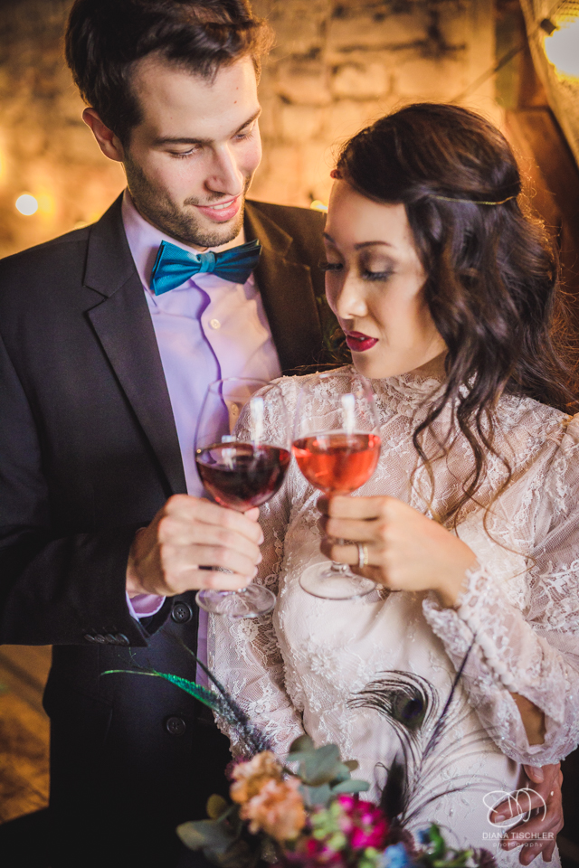 Brautpaar stoesst mit Wein an bei einer Hochzeit in einer Scheune