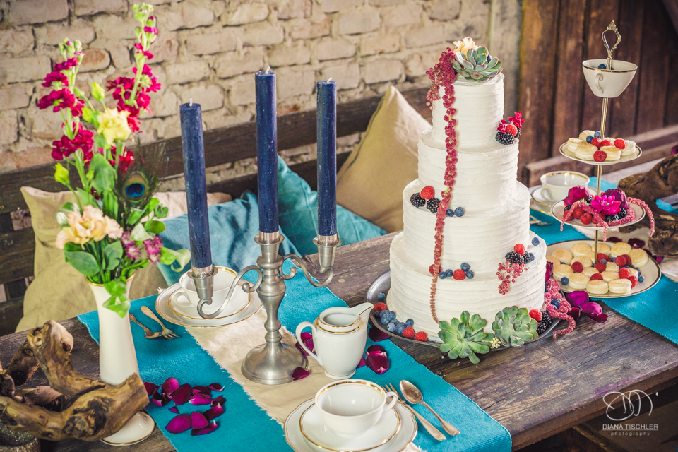 Tischgedeck und Dekoration und Torte fuer eine Hochzeit in einer Scheune