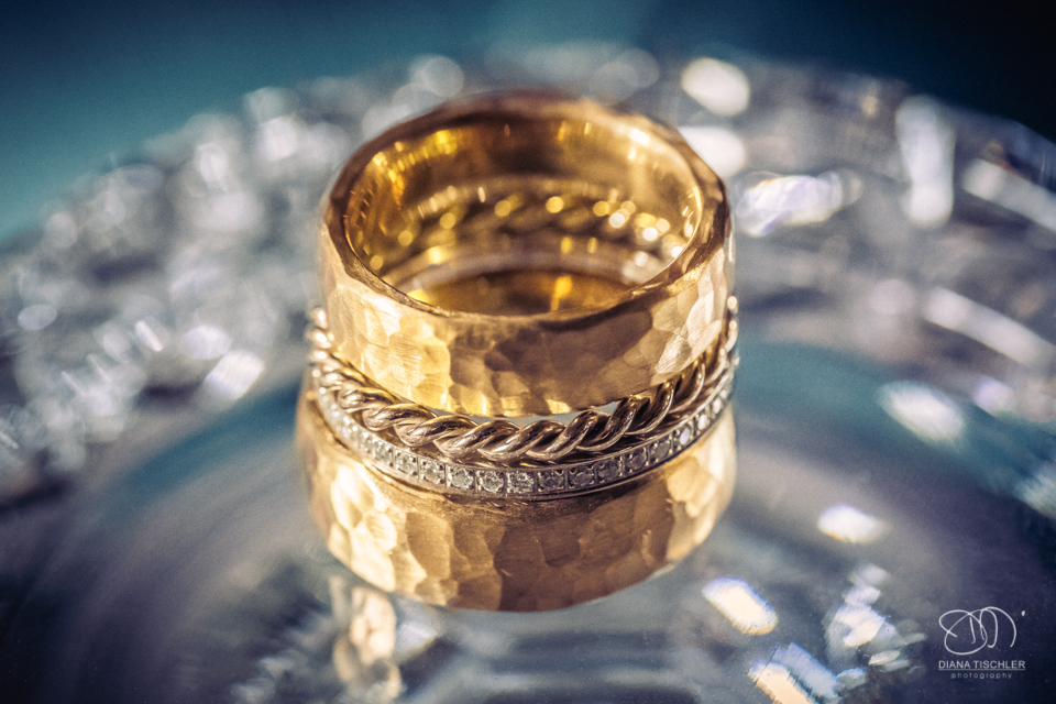goldene Eheringe mit Verlobungsring bei einer Hochzeit in einer Scheune