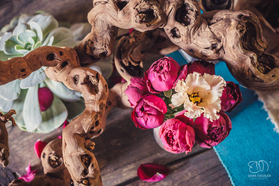 Bunte Blumen-Dekoration auf einem Vintage Esstisch fuer eine Hochzeit in einer Scheune