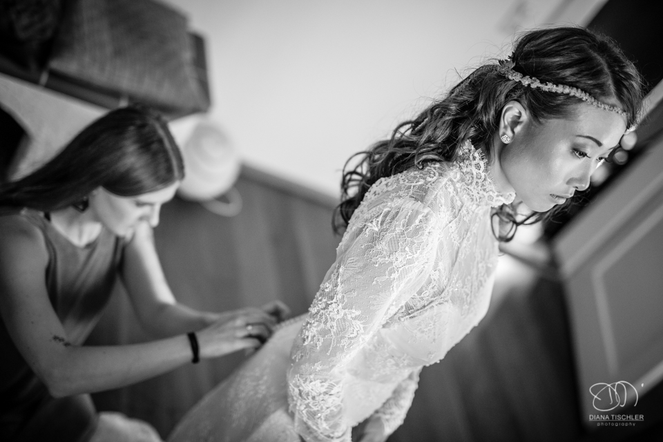 Getting Ready Schwarzweiss Brautkleid knoepfen fuer eine Hochzeit in einer Scheune