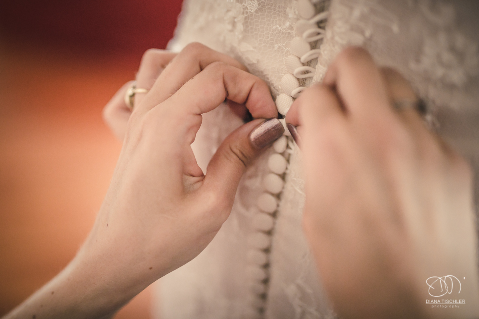 Getting Ready Brautkleid knoepfen fuer eine Hochzeit in einer Scheune