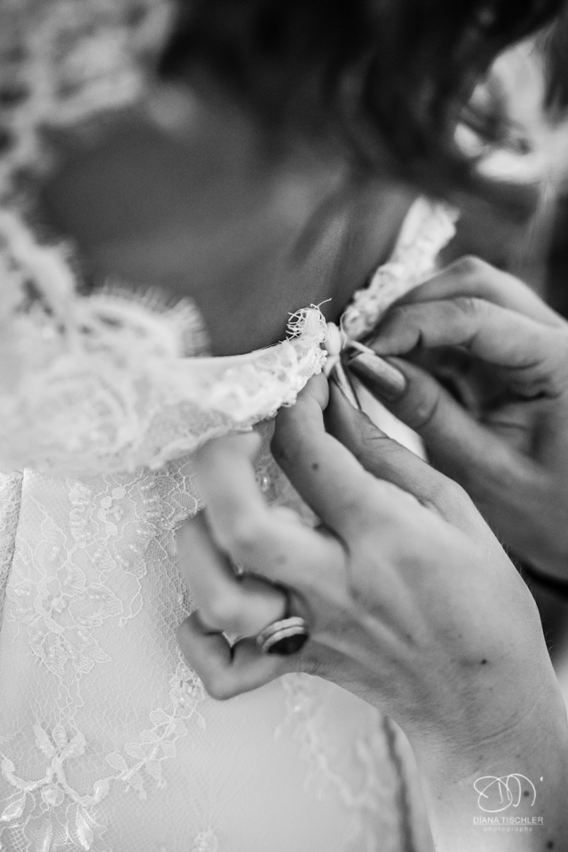 Getting Ready Schwarzweiss Brautkleid knoepfen fuer eine Hochzeit in einer Scheune