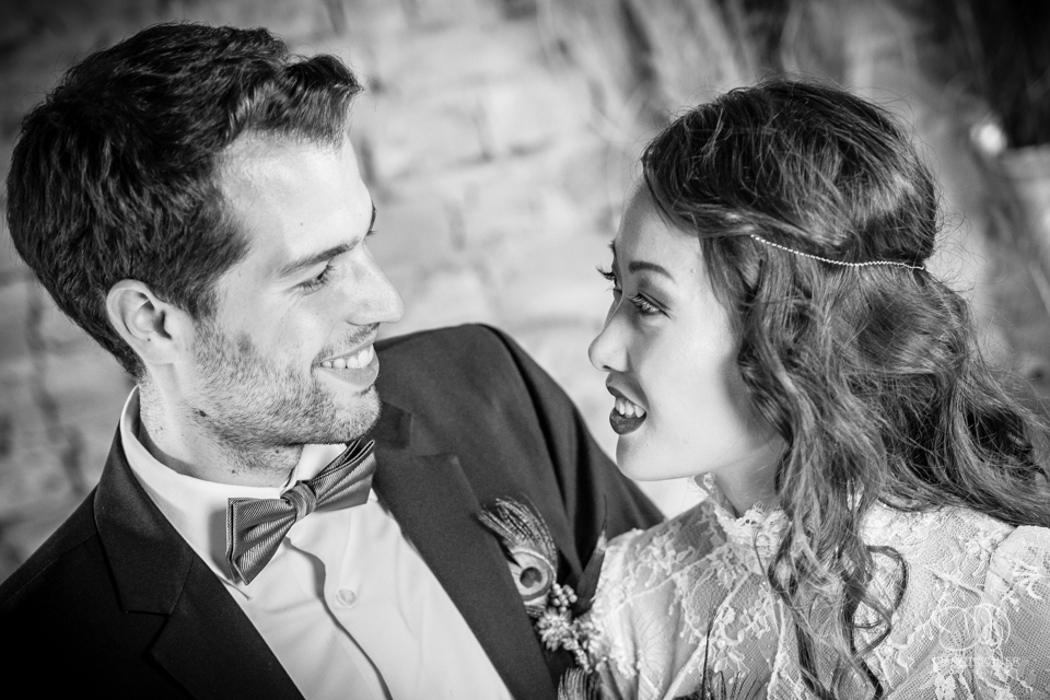 Braeutigam und Braut lachen sich an beim Getting Ready fuer eine Hochzeit in einer Scheune