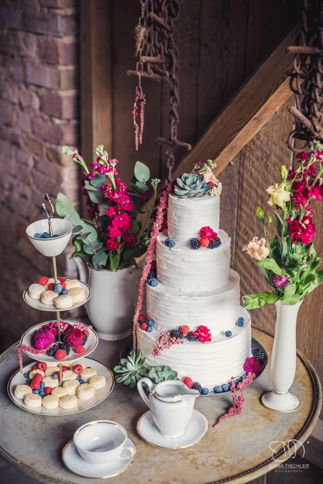 Hochzeitstorte mit Beeren und Blumen fuer eine Hochzeit in einer Scheune
