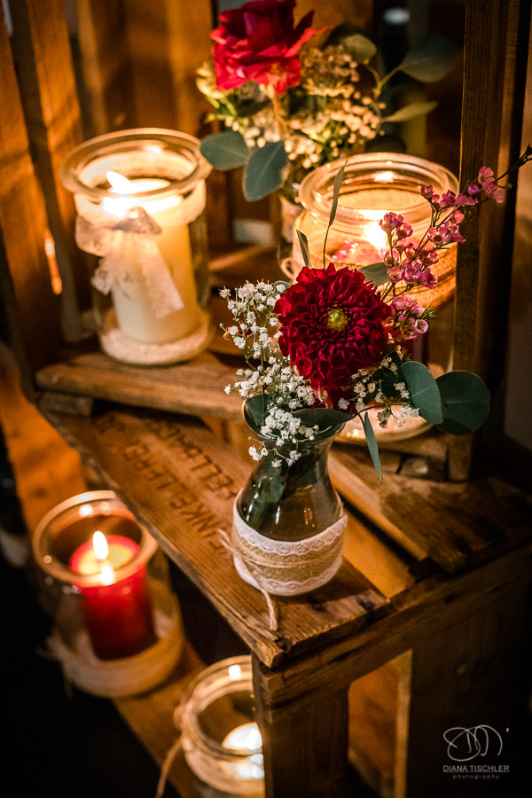 Dekoration mit Kerzen im Glas mit roten Blumen auf alten Weinkisten im Festsaal bei einer Hochzeit in der WG Brackenheim