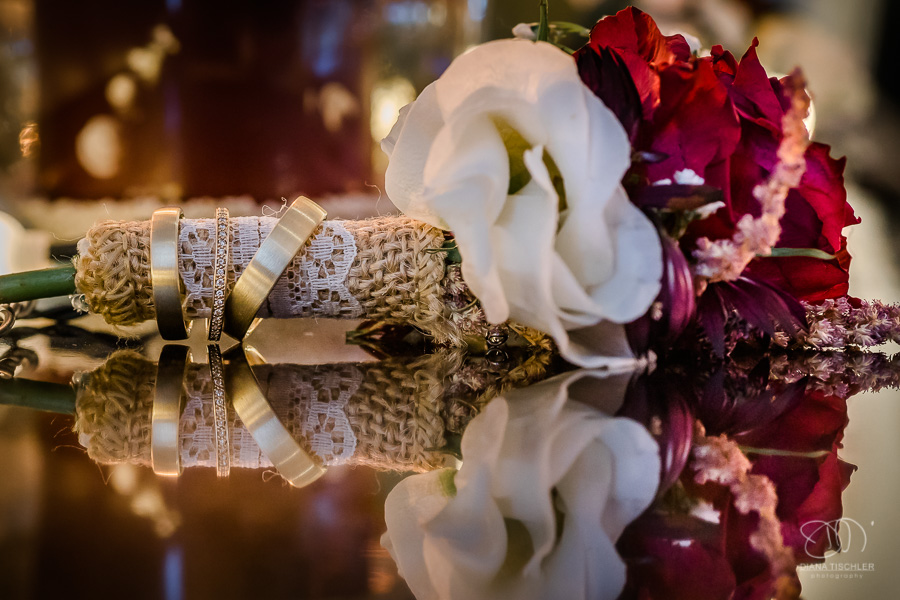 Rose umwickelt mit Juteband und Eheringen mit Spiegelung im Abendlicht im Festsaal bei einer Hochzeit in der WG Brackenheim