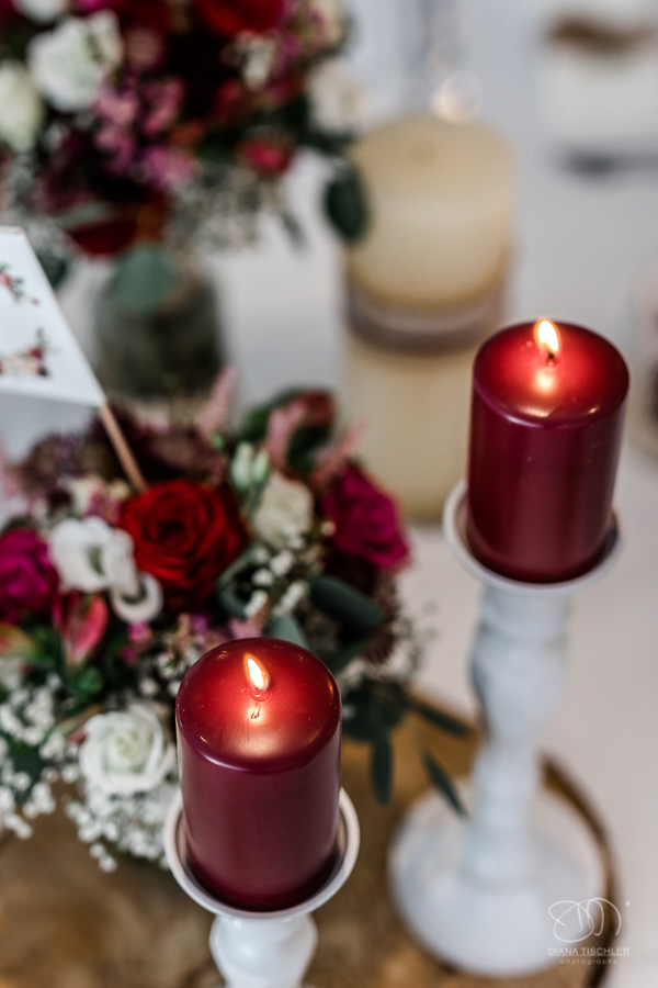 Dekoration brennende rote Kerzen mit Blumendeko auf dem Brauttisch im Festsaal bei einer Hochzeit in der WG Brackenheim