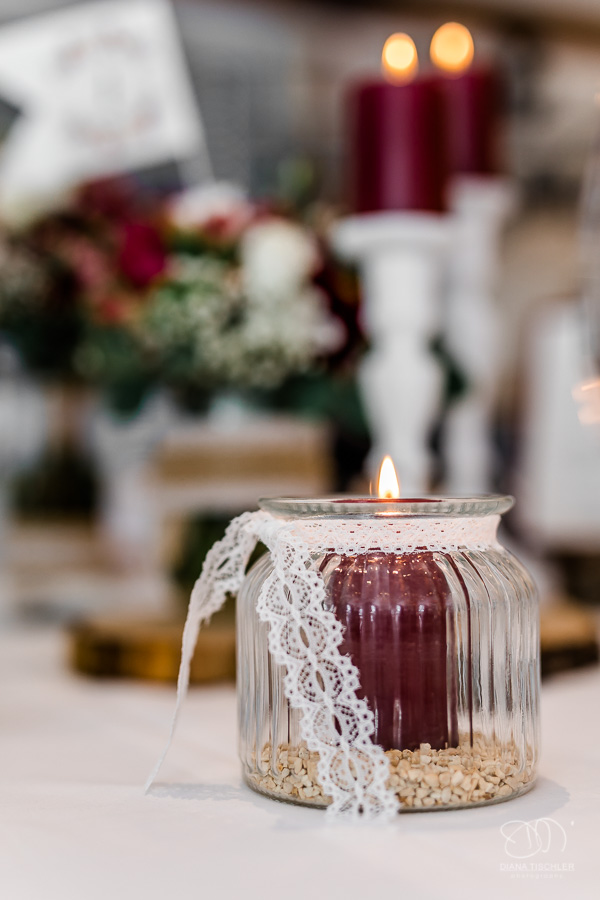 Brennende Kerze im Glas mit Spitzenband Tischdekoration bei Hochzeit