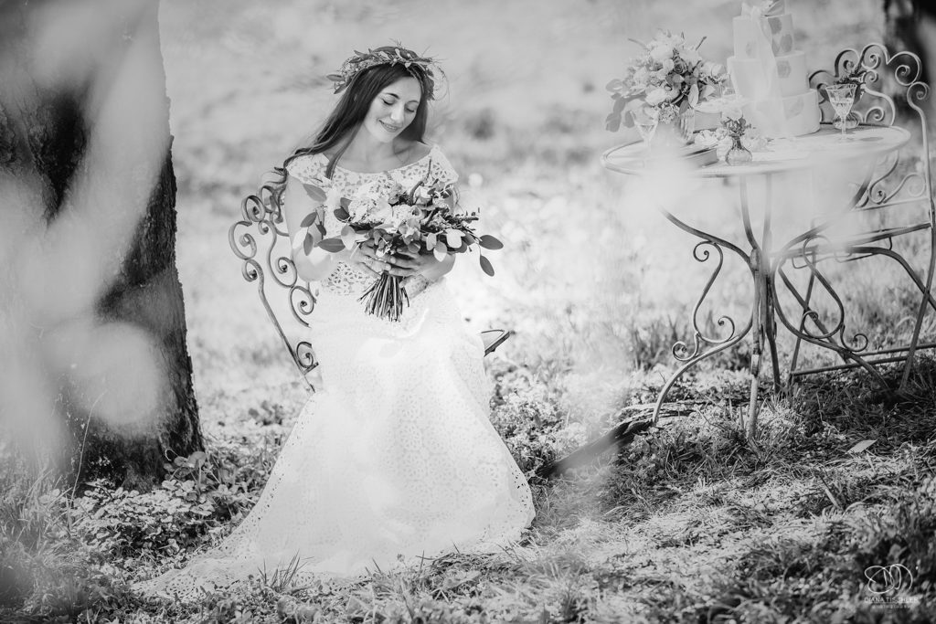 Braut mit Brautstrauss sietzt an vintage Tisch Schwarzweissfoto