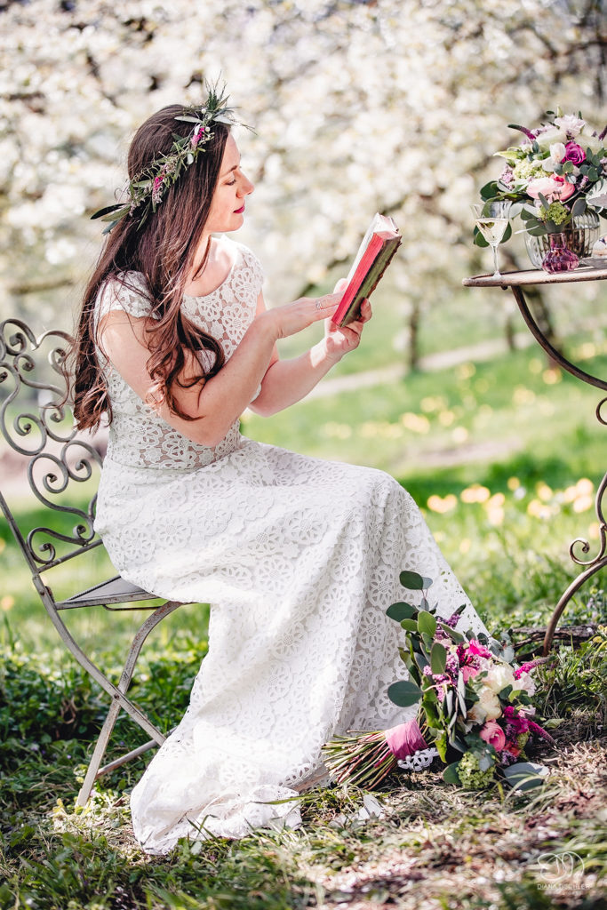 Braut mit altem Buch auf Wiese