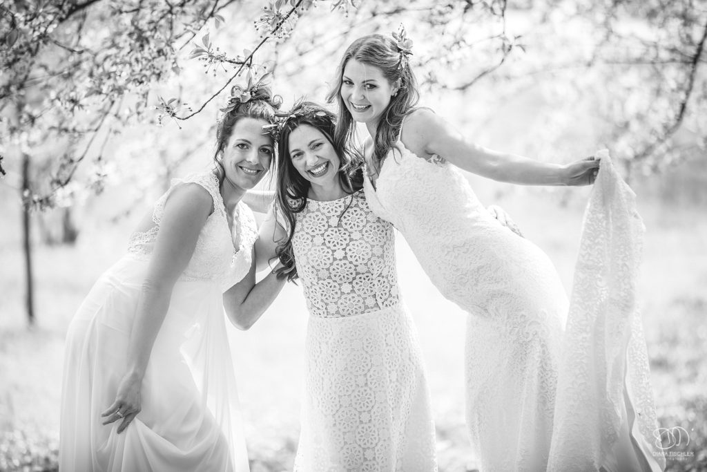 Bräute lachen zusammen auf einer Wiese im Frühling Leistungen Hochzeitsfotograf