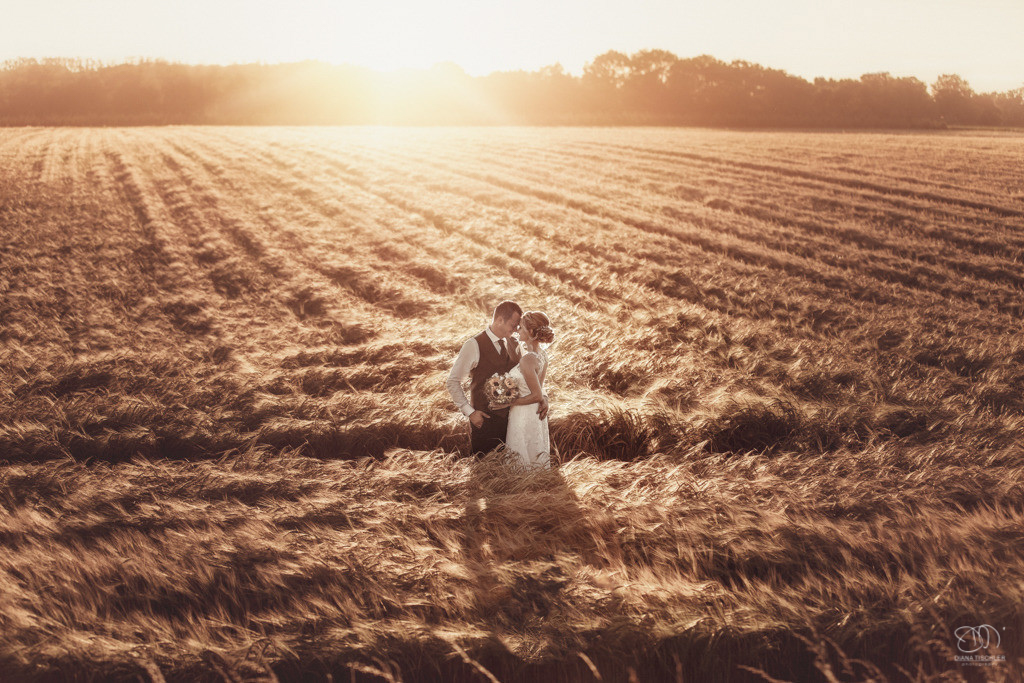 Brautpaar im Feld in tollem Licht bei Sonnenuntergang lachend / Hochzeitsfotos