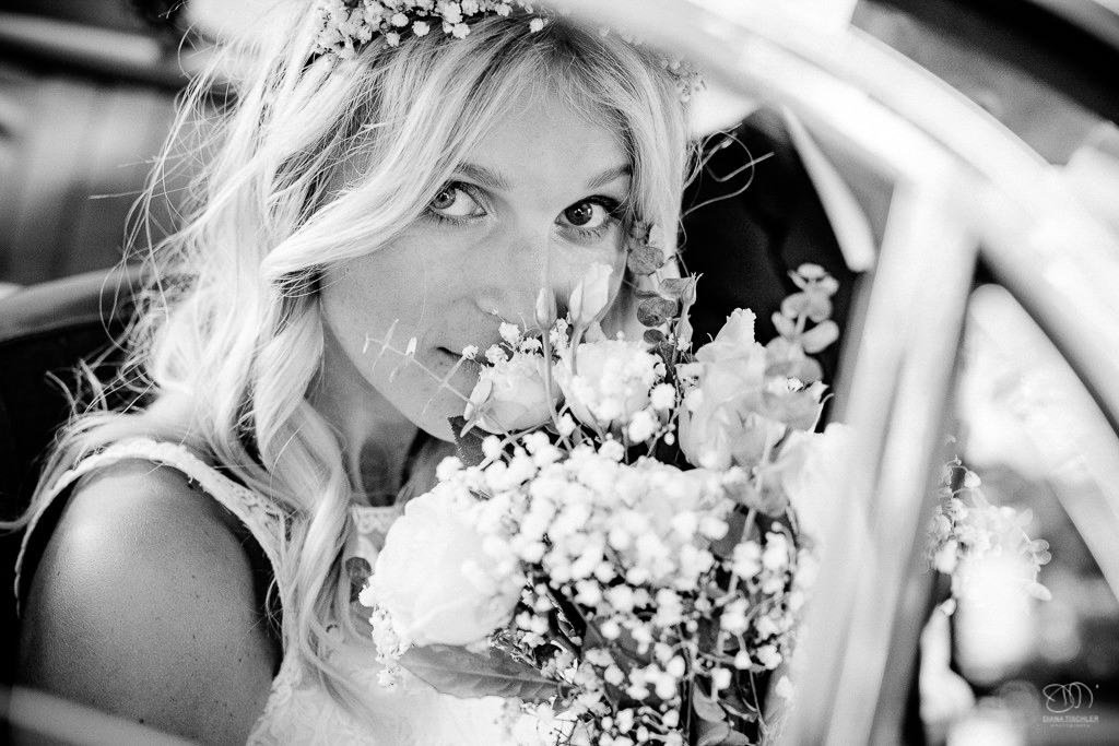 Braut mit Brautstrauss im Oldtimer schaut in die Kamera Schwarzweissfoto / Hochzeitsfotograf Stuttgart