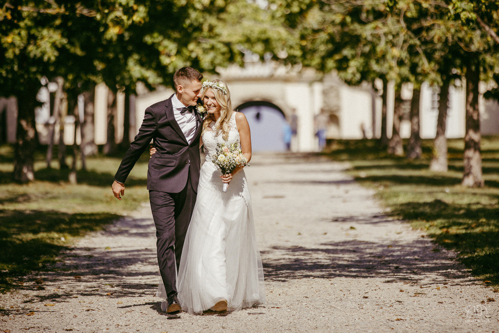 süßes Brautpaar auf dem Weg beim Schloss Solitude läuft lachend auf den Fotografen zu Leistungen Hochzeitsfotograf Stuttgart