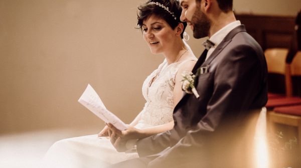 Brautpaar bei der Hochzeit singt aus dem Liedblatt Hochzeitsfotograf